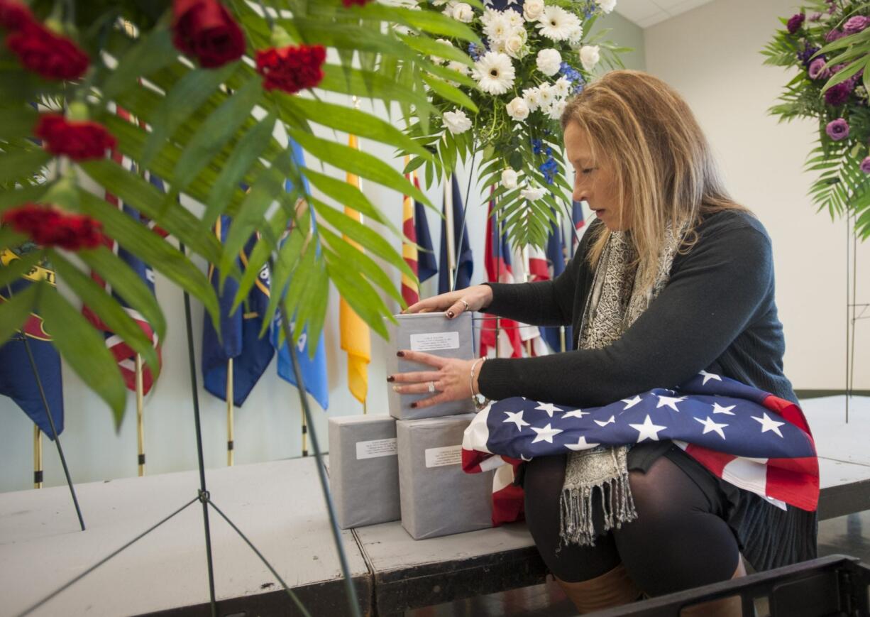 Elizabeth Johnston, family assistance specialist with the Washington Army National Guard, arranges containers holding the cremated remains of five veterans before Thursday&#039;s memorial ceremony. Veterans Ivan E. Bennett, Carl E. Walters, Loreing L. Lehmann, Robert M. Guentner and Harry W. Verrell were saluted at the event.