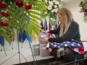 Elizabeth Johnston, family assistance specialist with the Washington Army National Guard, arranges containers holding the cremated remains of five veterans before Thursday&#039;s memorial ceremony. Veterans Ivan E. Bennett, Carl E. Walters, Loreing L. Lehmann, Robert M. Guentner and Harry W. Verrell were saluted at the event.