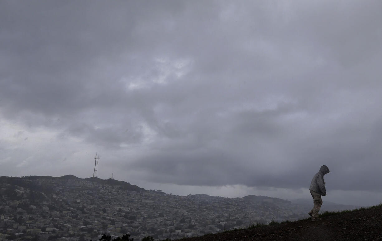 A man walks amid rain and hail up Bernal Heights Hill on Monday in San Francisco. Powerful thunderstorms moved swiftly through California on Monday, briefly knocking out power to Los Angeles&#039; airport and walloping the Sierra Nevada with blizzard conditions.