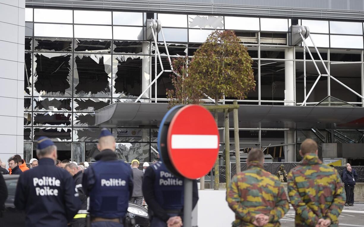 Police and soldiers from the Belgian Army stand in front of blown out windows at Zaventem Airport in Brussels on Wednesday, March 23, 2016. Belgian authorities were searching Wednesday for a top suspect in the country&#039;s deadliest attacks in decades, as the European Union&#039;s capital awoke under guard and with limited public transport after scores were killed and injured in bombings on the Brussels airport and a subway station.