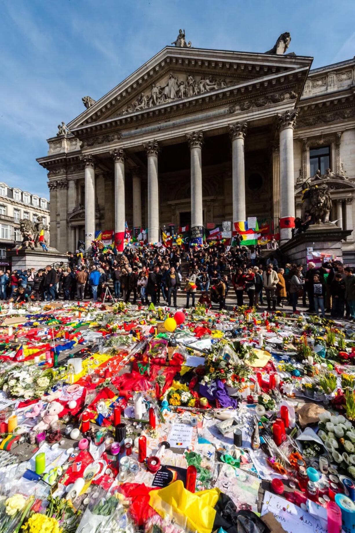 People gather around floral tributes Saturday at a memorial site at the Place de la Bourse in Brussels. Belgium&#039;s interior minister appealed to residents not to attend a planned march today in solidarity with the victims, saying police are stretched too thin. Organizers quickly granted his request, postponing the march.