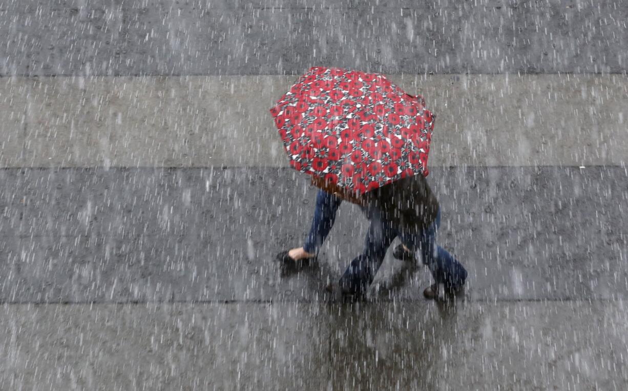 An umbrella is shared as rain pelts downtown Sacramento, Calif., Friday, March 4, 2016.