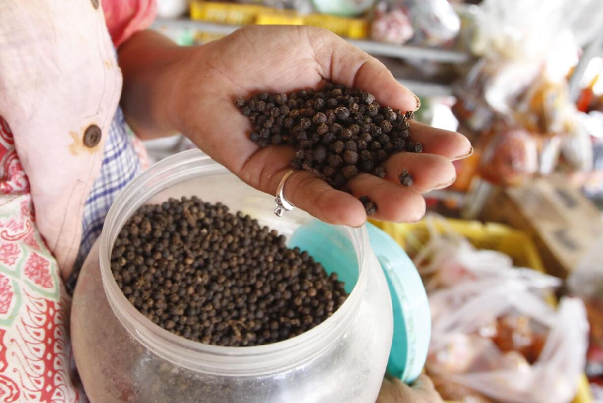 A vendor holds a handful of Kampot pepper Tuesday at a market in Phnom Penh, Cambodia.