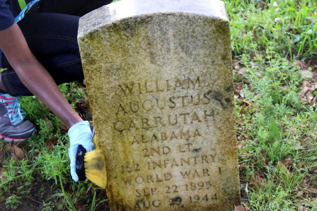 Volunteers spray a cleaning solution on gravestones at Chalmette National Cemetery in Chalmette, La. They were among about 50 Ohio State students working at the cemetery as part of a nearly month-long project organized by the National Trust for Historic Preservation.