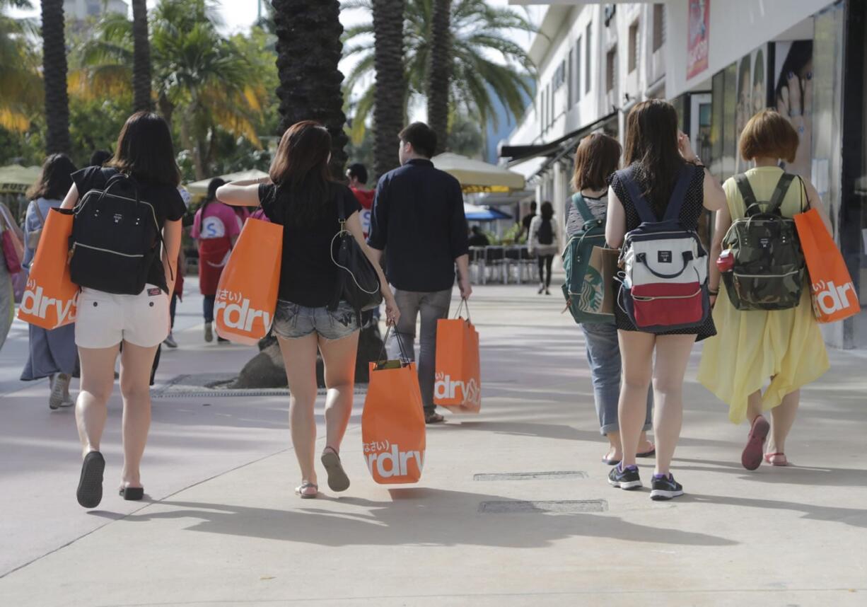 Tourists from Taiwan carry shopping bags Feb. 3 as they walk along Lincoln Road Mall, a pedestrian area featuring retail shops and restaurants in Miami Beach, Fla. On Friday, the Commerce Department issues the third and final estimate of how the U.S. economy performed in the October-December quarter.