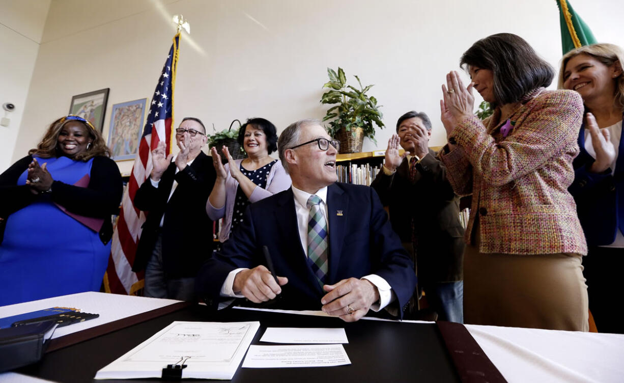 Gov. Jay Inslee is applauded by officials after signing House Bill 1541 at Aki Kurose Middle School, Wednesday in Seattle. Inslee signed the bill aimed at closing the so-call opportunity gaps faced by kids from low-income and minority families.