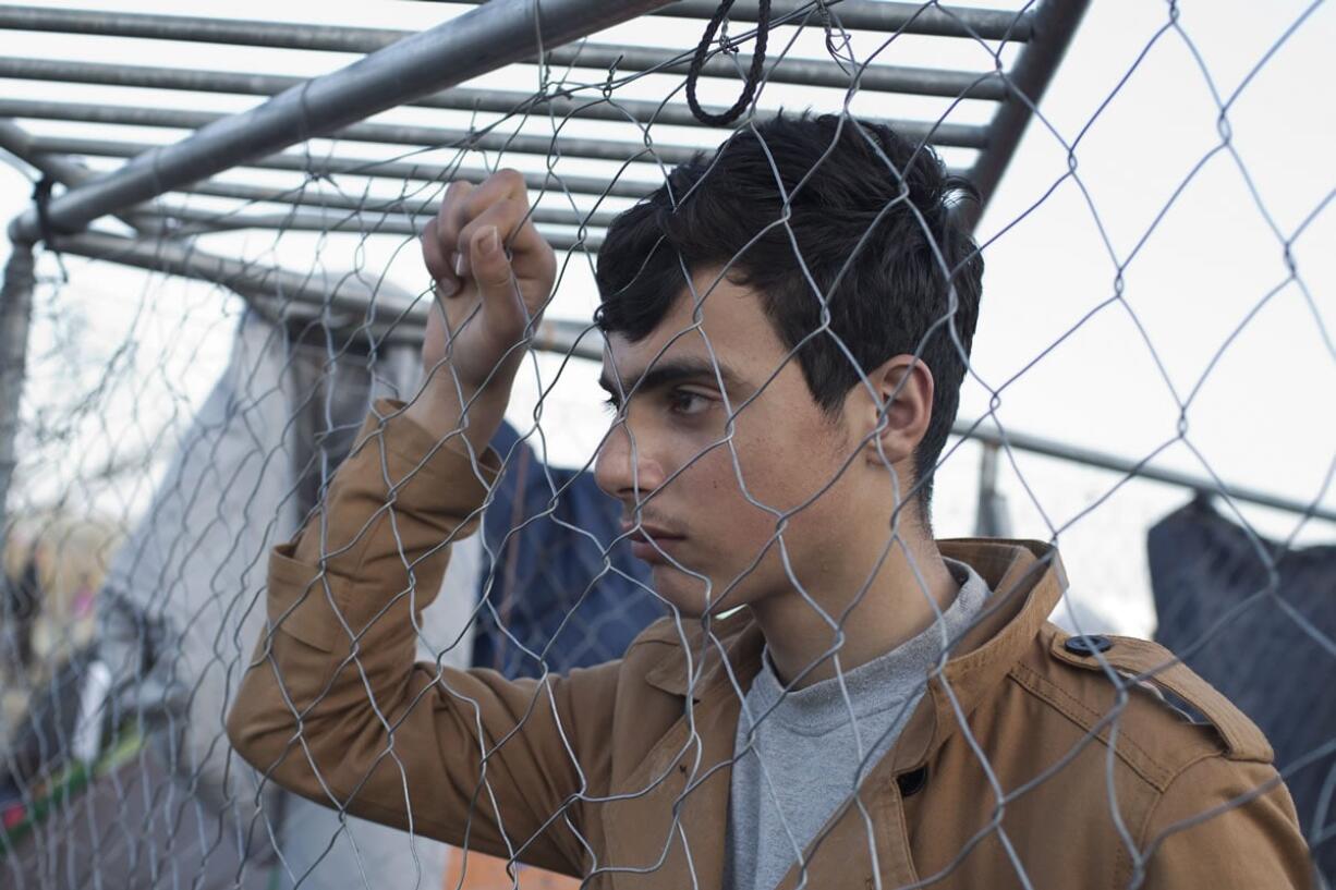 A young man looks across the border as refugees and migrants wait to be allowed to cross into Macedonia on Tuesday in Idomeni, Greece.