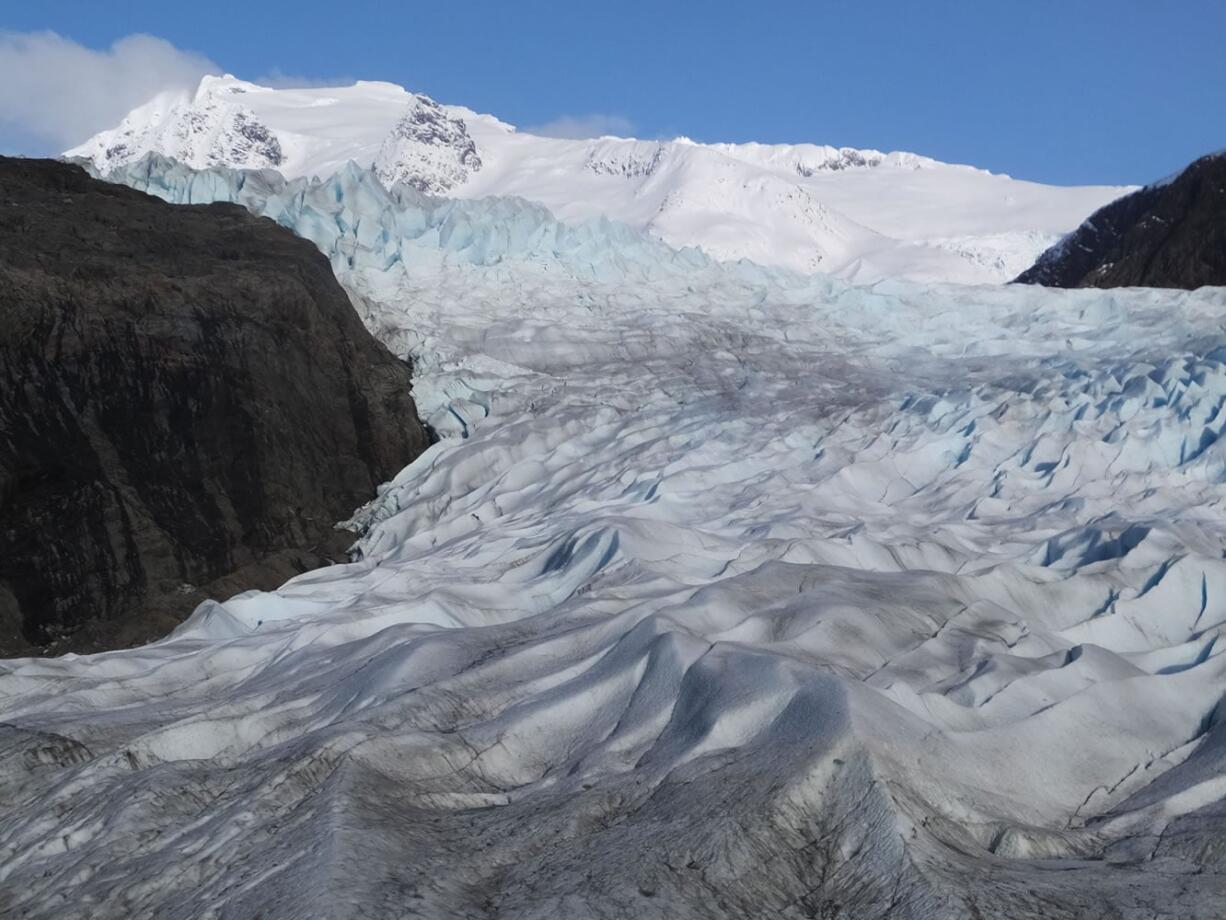 FILE- In this Feb. 15, 2016 file photo, snow-covered mountains are seen behind the Mendenhall Glacier in Juneau, Alaska. The massive Alaska ice field that feeds Juneau&#039;s Mendenhall Glacier, a tourist attraction viewed by hundreds of thousands each year, could be gone by 2200 if climate warming trends continue, according to a new University of Alaska Fairbanks study.