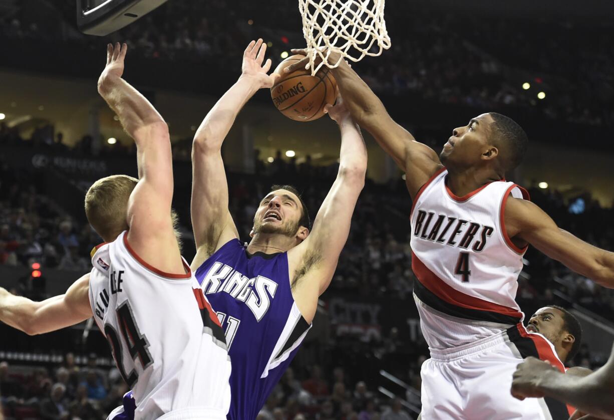 Portland Trail Blazers forward Maurice Harkless (4) blocks the shot of Sacramento Kings center Kosta Koufos as center Mason Plumlee (24) defends during the first quarter of an NBA basketball game in Portland, Ore., Monday, March 28, 2016.