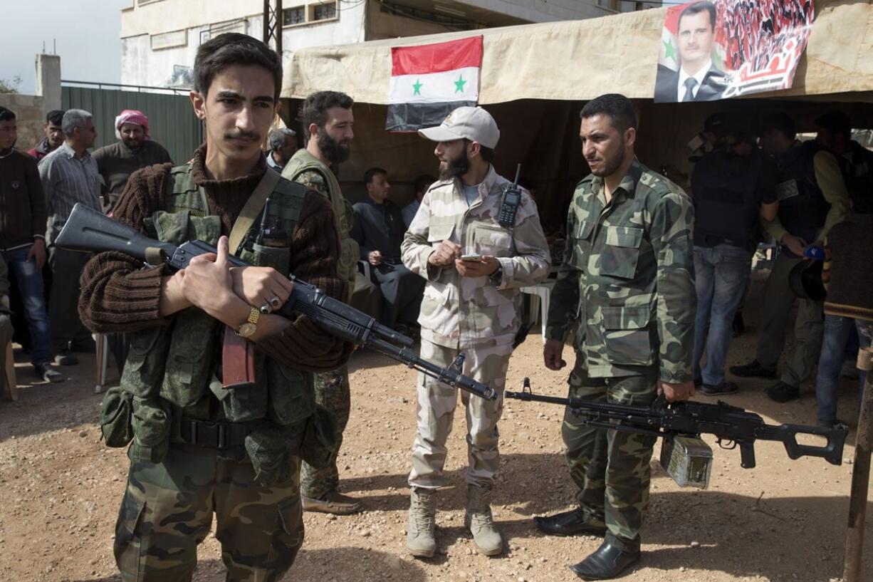 In this photo taken on Wednesday, March 2, 2016, Syrian solders guard near a tent where local leaders and elders signed a declaration pledging to abide by a truce Maarzaf, about 15 kilometers west of Hama, Syria.  Associated Press spent five days traveling through the port of Latakia and the surrounding areas in Syria during the cease-fire.