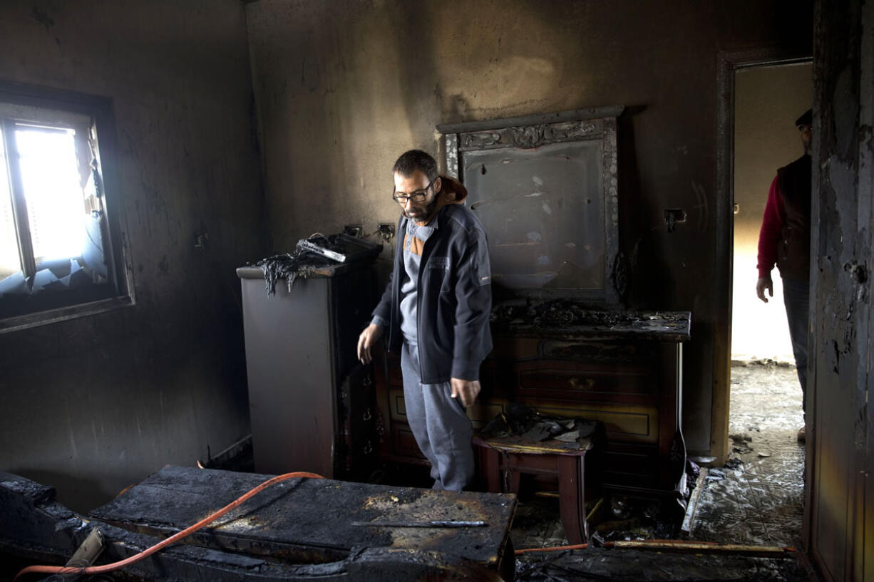 A Palestinian man inspects a house that was torched in the Palestinian village of Duma near the West Bank city of Nablus, Sunday, March 20, 2016. A Palestinian home near the site of an arson attack that killed three Palestinians last year caught fire early Sunday, Israeli and Palestinian officials said, with immediate suspicion falling on Jewish extremists.