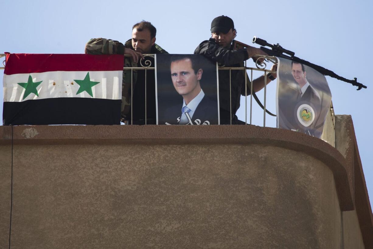 Syrian solders keep watch Thursday on a roof adorned with portraits of Syrian President Bashar Assad in Al-Tall, a town of the northern outskirts of Damascus. Al-Tall has seen its population increase sharply as it hosts large numbers of refugees from other areas in Syria.