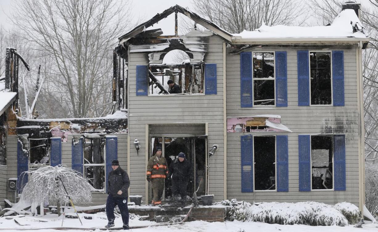 Investigators search the site of a Jan. 11 house explosion where a family of four was found dead in Northfield Center Township, Ohio. The Summit County, Ohio, medical examiner said Thursday that two girls found dead inside the home were either strangled or smothered, their mother died of a Prozac overdose and their father, who authorities say set the fire using gasoline, died of burns.