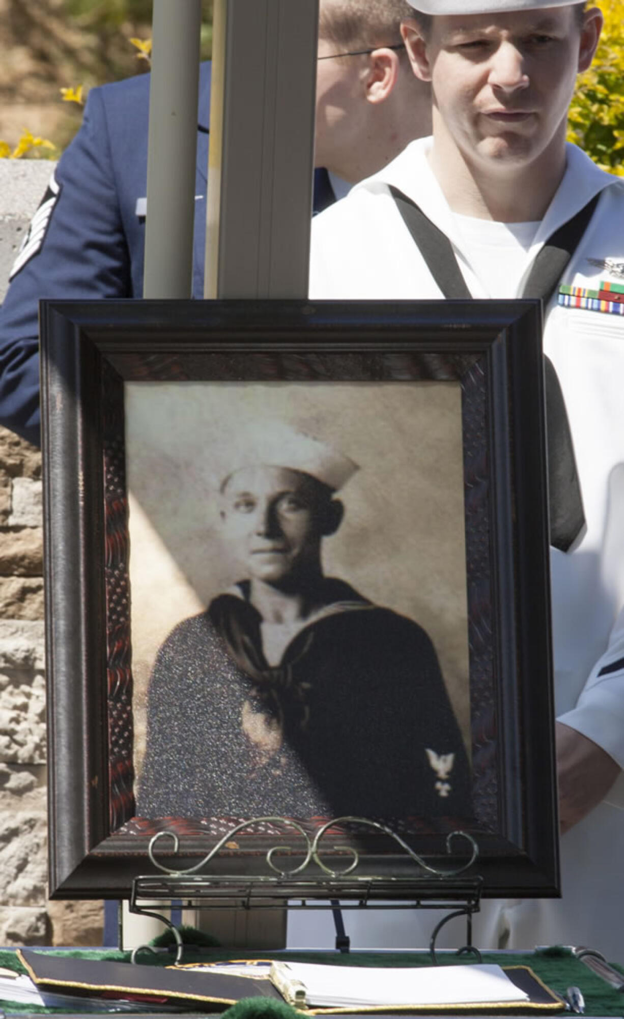 A Navy sailor stands next to a photograph of Petty Officer 1st Class Vernon Luke of Green Bay, Wis., a sailor killed in the attack on Pearl Harbor, at his funeral Wednesday in Honolulu.