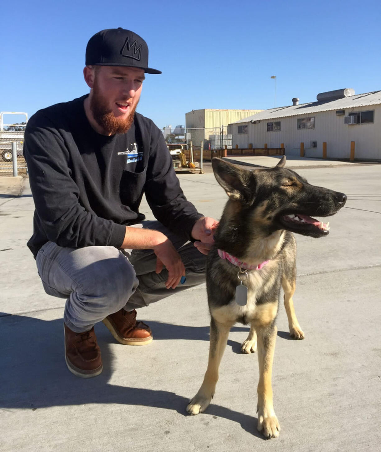 Conner Lamb squats next to Nick Haworth&#039;s 1 1/2-year-old German shepherd Luna, who fell overboard from his boat in the ocean off the Southern California coast in February, arrives at Naval Base Coronado in San Diego on Wednesday. Luna was found Tuesday on San Clemente Island, a Navy-owned training base. Haworth was working on a boat two miles from the island when Luna disappeared Feb. 10. (U.S.