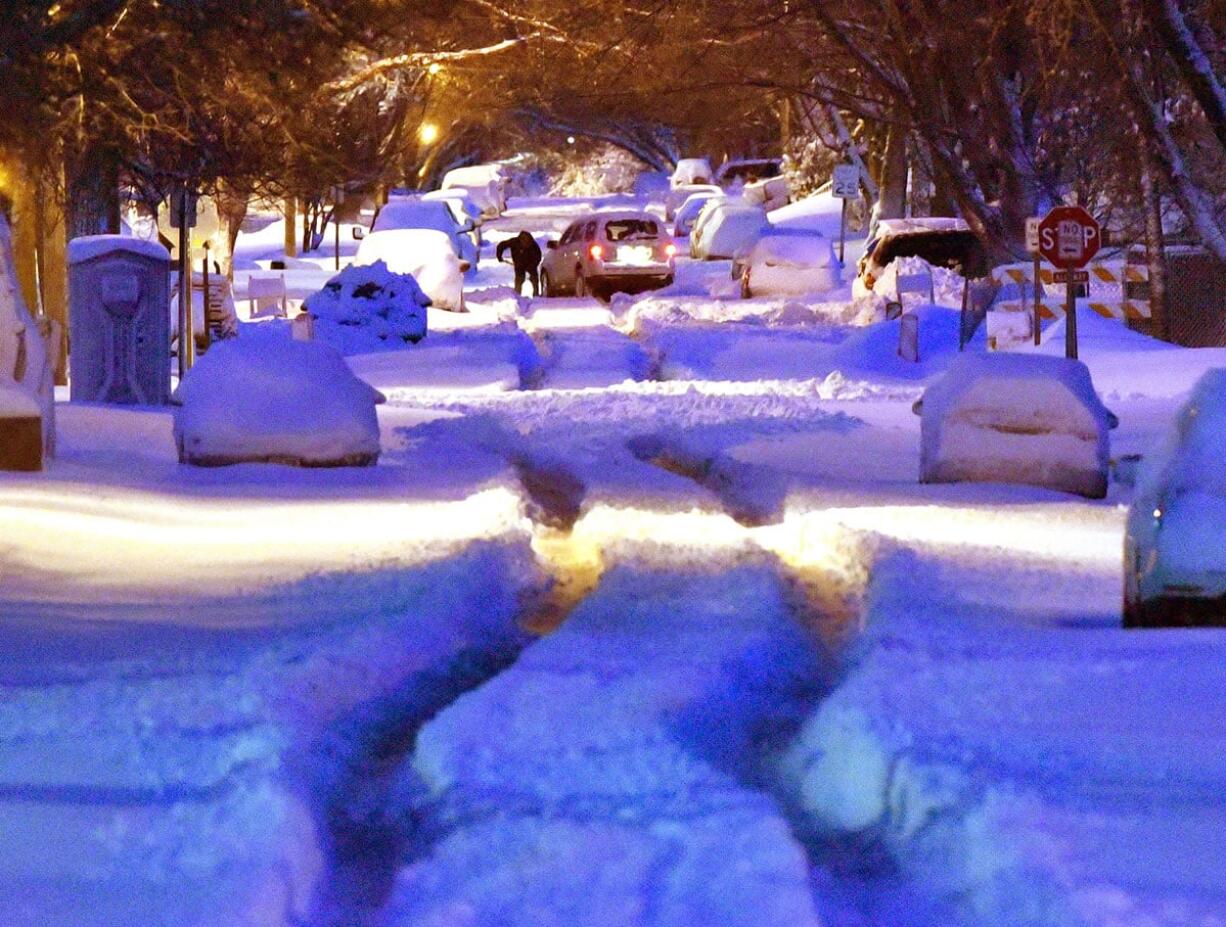 A person early Thursday digs out a vehicle stuck in the middle of a Sioux City, Iowa, street. A spring snow storm dropped about 14 inches of snow in the area.