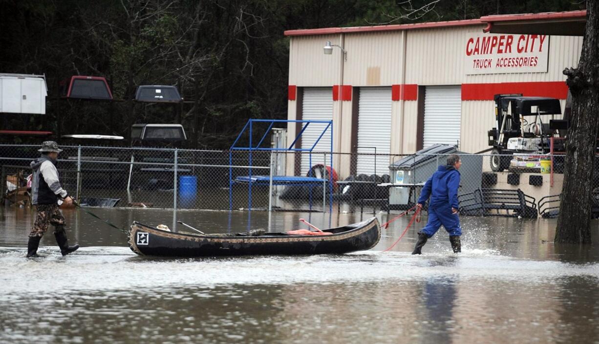 Men pull a canoe past a flooded business Saturday along U.S. Highway 49 in Hattiesburg, Miss. More than 10 inches of rain fell in the area over the last two days.