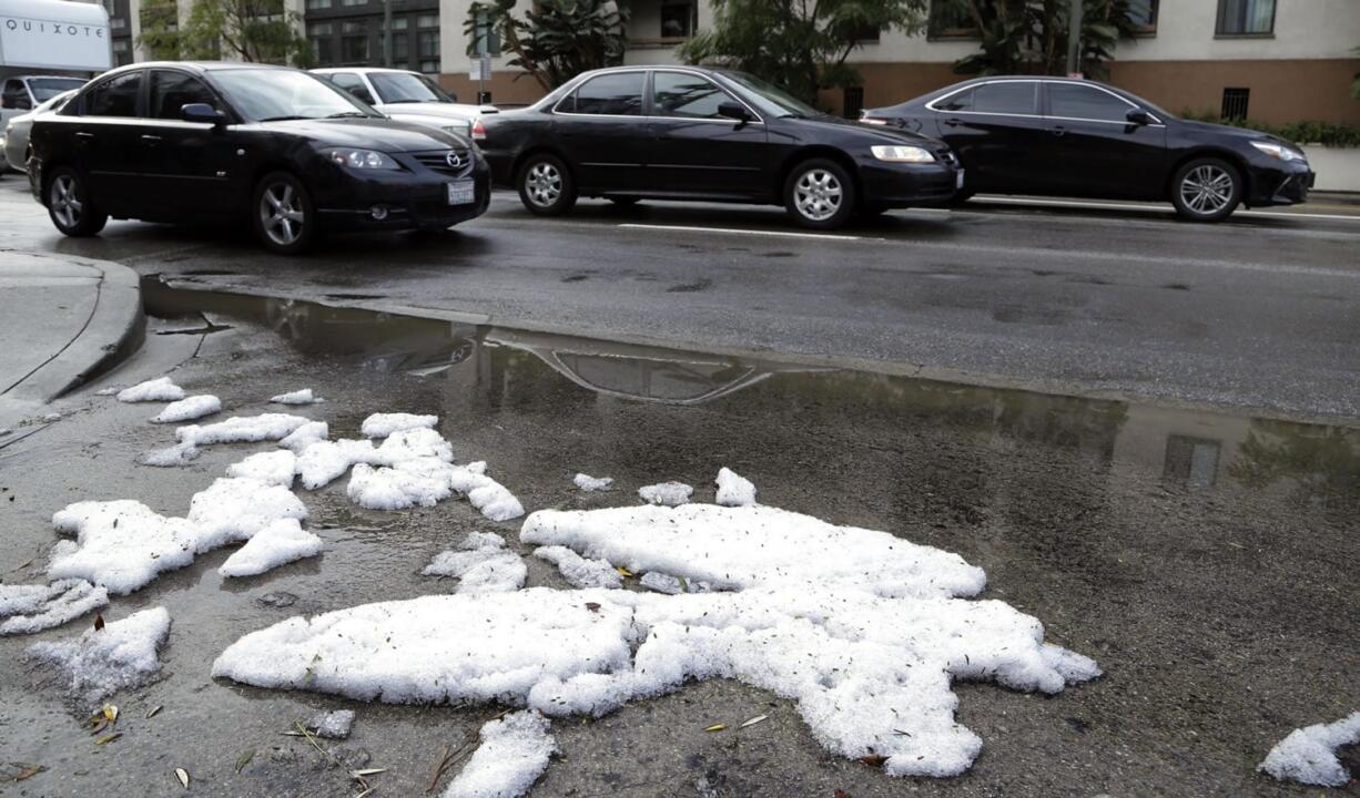 Commuters drive down a street that is covered with hail after a heavy rain storm drenched downtown Los Angeles on Monday,. Thunder crashed and lightning struck as powerful thunderstorms moved swiftly through California Monday, briefly knocking out power to Los Angeles&#039; airport and walloping the Sierra Nevada with blizzard conditions.