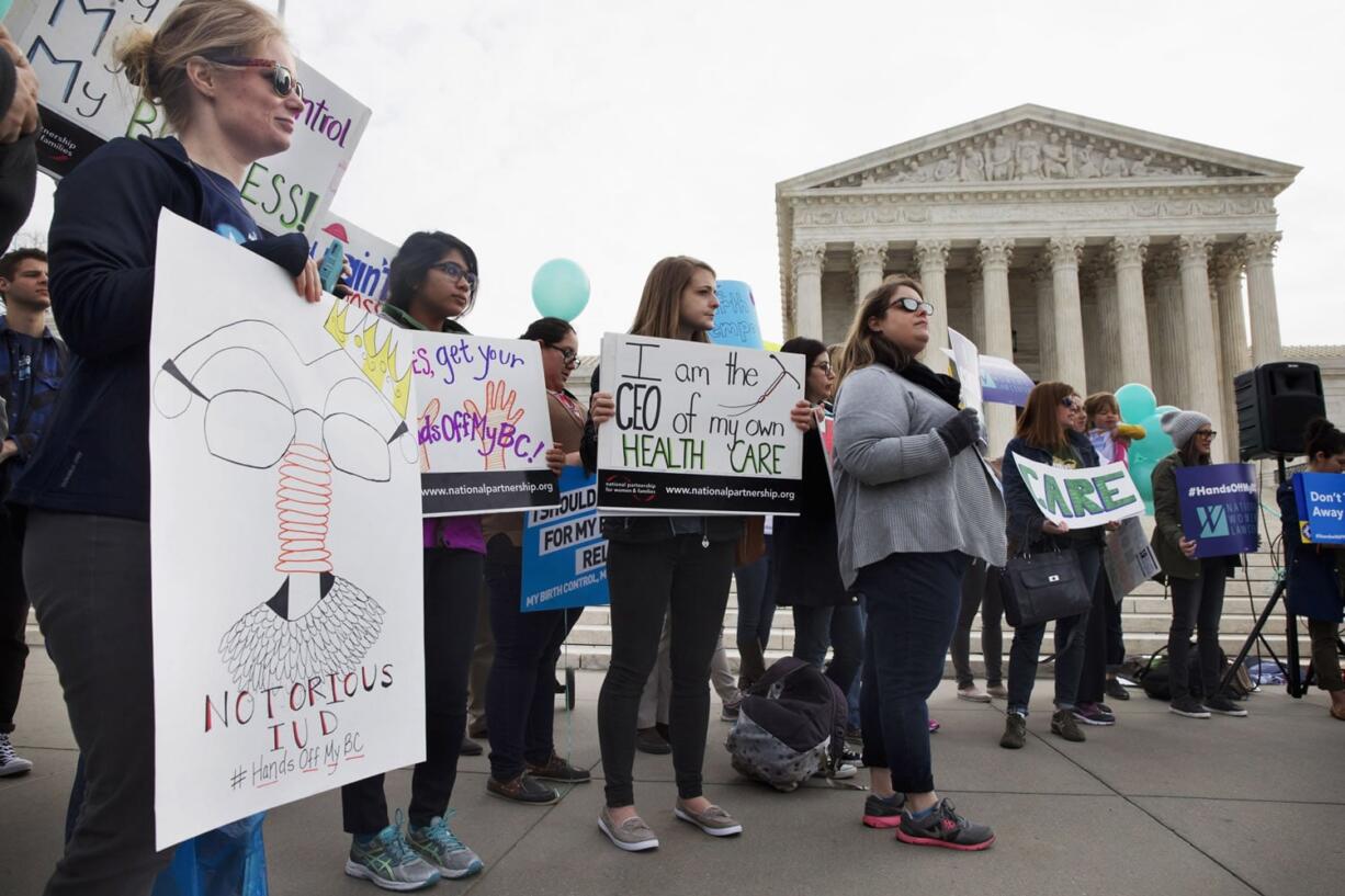 Kate Perelman of Silver Spring, Md., left, with Americans United for Separation of Church and State, holds a sign saying &quot;Notorious IUD&quot; as a play on words with the nickname for Supreme Court Justice Ruth Bader Ginsburg, as she, and others, rally in support of birth control access regardless of employer outside the Supreme Court in Washington. The Supreme Court is taking up a challenge from faith-based groups that object to an Obama administration effort to ensure their employees and students can get cost-free birth control.