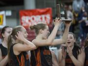 Washougal High School’s Raeann Allens hoists the fourth-place trophy as she and her teammates celebrate after beating Black Hills High School 50-28 in the class 2A girls state basketball tournament March 5, 2016 in the Yakima SunDome in Yakima, Wash.