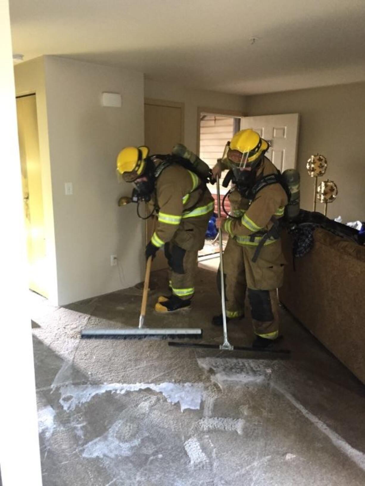 Firefighters help clean up the extensive water damage after a dryer caused a blaze in a Battle Ground apartment unit.