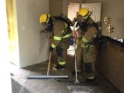 Firefighters help clean up the extensive water damage after a dryer caused a blaze in a Battle Ground apartment unit.