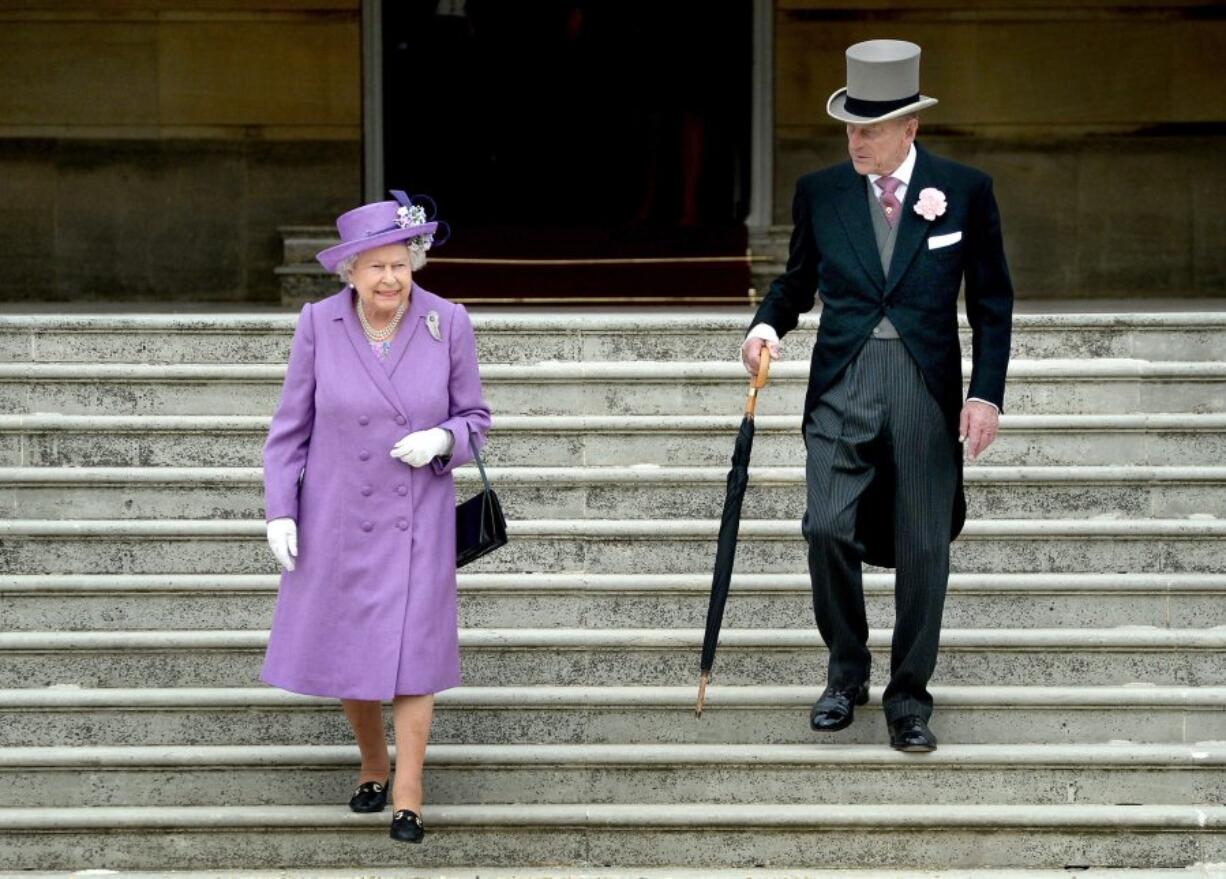 Britain&#039;s Queen ELizabeth II, shown here in 2014, carries her black handbag nearly everywhere in public. She even signals her staff with how she positions it.