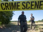 Clark County Sheriff&#039;s Office Detectives Joe Swenson, left, and Scott Gilberti investigate the homicide of Robert Huggins after loggers found his body in a field in Ridgefield on July 1.