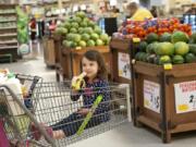 Maisy Fels, 3, of Vancouver snacks on a free banana while shopping with her grandmother Katy Miller on Tuesday afternoon at the Fisher&#039;s Landing Fred Meyer. The grocery chain recently launched its Fruit for Kids program that offers children a free piece of fruit while shopping.