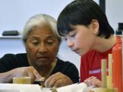 Bernice Akamine, left, helps 12-year-old Davin Carsten of Vancouver carve a pattern into a piece of bamboo Sunday afternoon during a stamp-making workshop at Clark College. Akamine&#039;s art is included in a show titled &quot;Woven: The Art of Contemporary Native Basketry&quot; at the college&#039;s Archer Gallery.