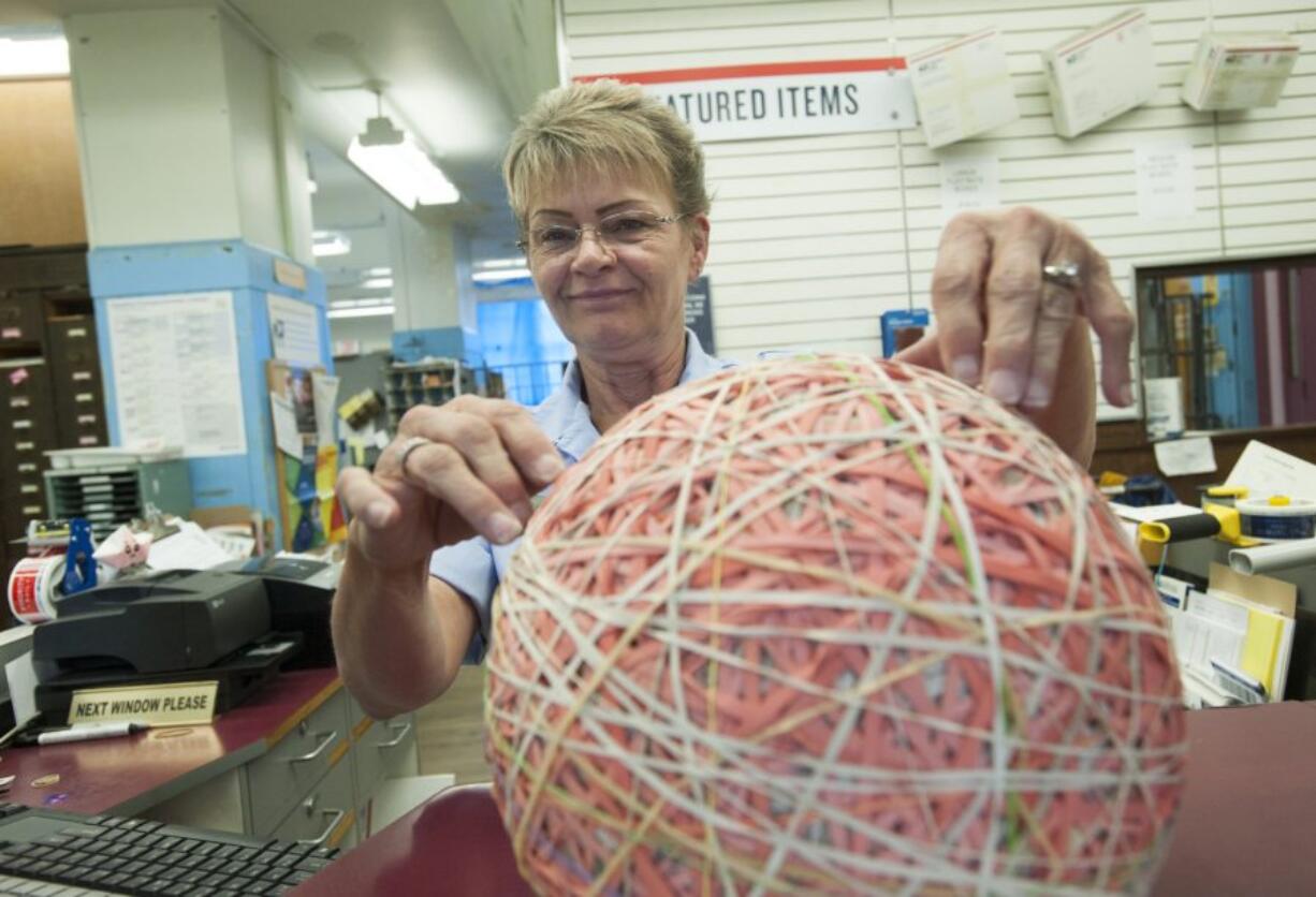 Postal worker Connie Brown adds another a rubber band Thursday to the big ball at the downtown Vancouver post office. Brown said she has been working on the project for more than four years.