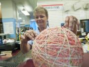 Postal worker Connie Brown adds another a rubber band Thursday to the big ball at the downtown Vancouver post office. Brown said she has been working on the project for more than four years.