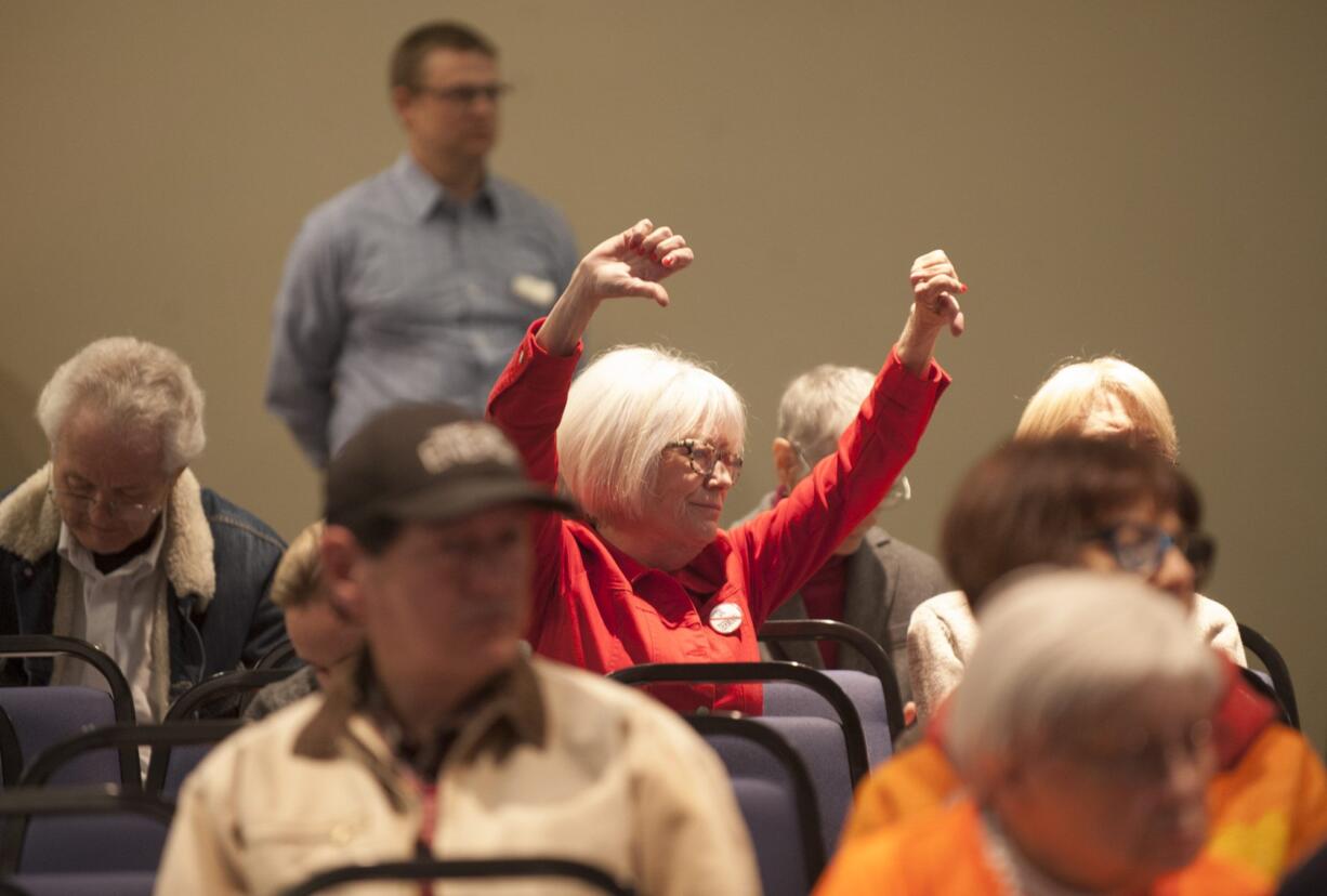 Nancy Shultz gives a thumbs down gesture as she listens to a speech in support of extending the oil terminal lease, at a hearing held by the Port of Vancouver at Clark College in Vancouver on Tuesday.