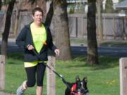 Jeanne Stevenson jogs with a dog as she trains for the upcoming 5K Walk/Run for the animals hosted by the Humane Society for Southwest Washington.