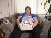 Kay Roberson, at her Vancouver home with her cat Sophie, holds a box of medications she&#039;s been prescribed for diagnosed mental health issues and several chronic health issues. Roberson spent most of her life on Medicaid.