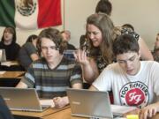 Woodland High School history teacher Katie Klaus works with junior history students Isaac Warner, left, and Matt Hambrook during a class project about World War II leaders.