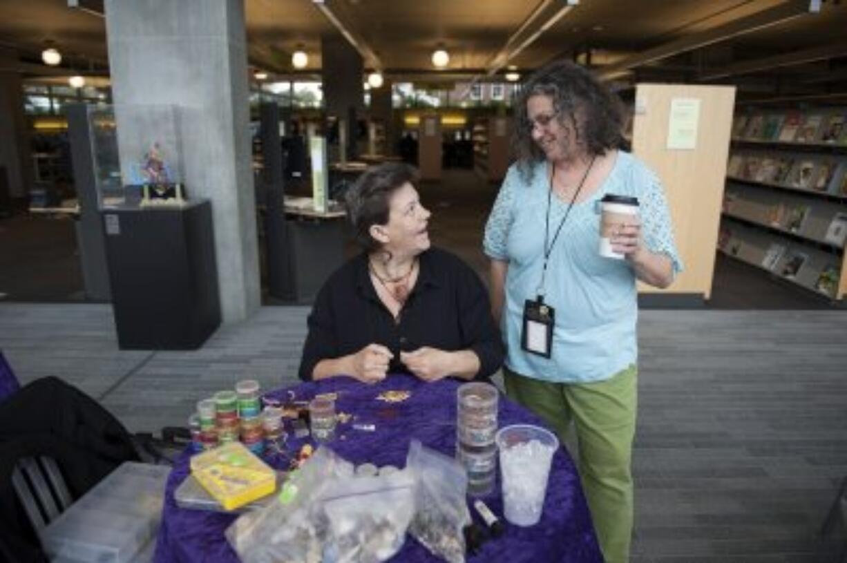 Mandi Vee, left, talks with Vancouver Community Library employee Ruth Shafer while working on a beading project. The two are planning an art gallery featuring artwork done by homeless people.