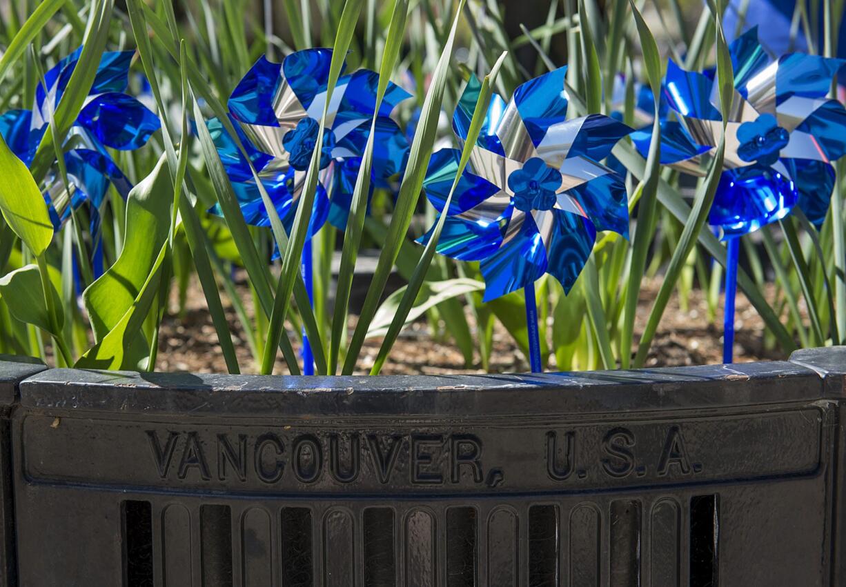 Sparkling blue pinwheels spin Friday afternoon in a planter at Esther Short Park in Vancouver, part of a national effort to raise awareness for child abuse prevention.