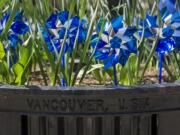 Sparkling blue pinwheels spin Friday afternoon in a planter at Esther Short Park in Vancouver, part of a national effort to raise awareness for child abuse prevention.