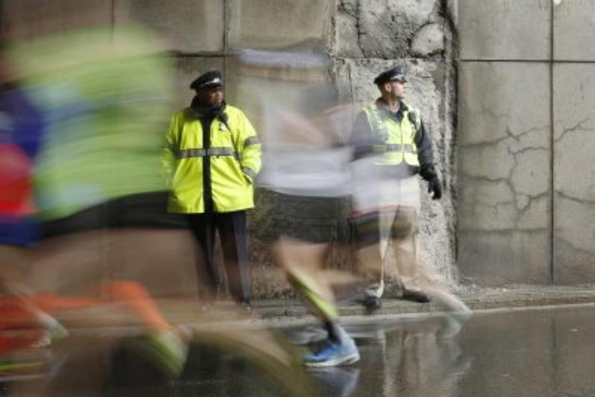 Police officers stand watch as 2015 Boston Marathon participants race along the course in Boston. Multiple law enforcement agencies will provide security for the 120th Boston Marathon set to be run on Monday, April 18, 2016. (AP Photo/Robert F.