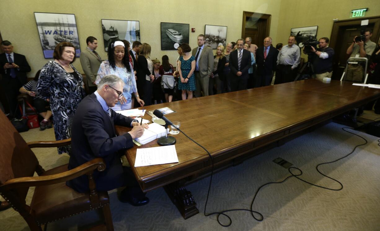 Washington Gov. Jay Inslee signs the state's supplemental budget, Monday, April 18, 2016, at the Capitol in Olympia, Wash. The budget puts more money into the state's mental health hospitals, pays for the costs of 2015's devastating wildfires, and was passed by the Legislature after a 20-day overtime legislative session. (AP Photo/Ted S.