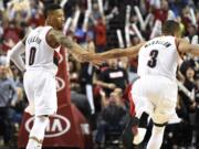 Blazers guard Damian Lillard (0) celebrates with teammate C.J. McCollum (3) after hitting a shot late in the fourth quarter against the Philadelphia 76ers.