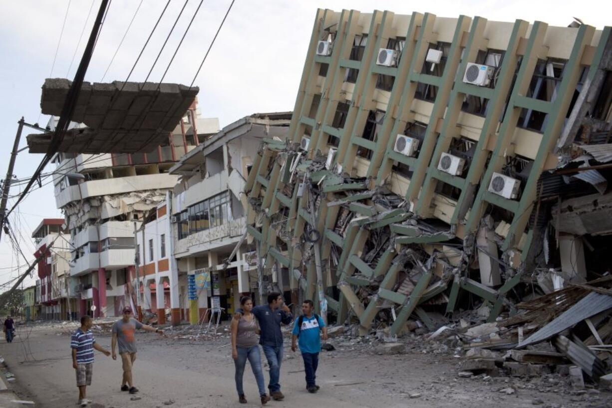 Residents walk past a row of collapsed buildings felled by the 7.8-magnitude earthquake, in Portoviejo, Ecuador, on Monday. The Saturday night quake left a trail of ruin along Ecuador?s normally placid Pacific Ocean coast. At least 350 people died and thousands are homeless.