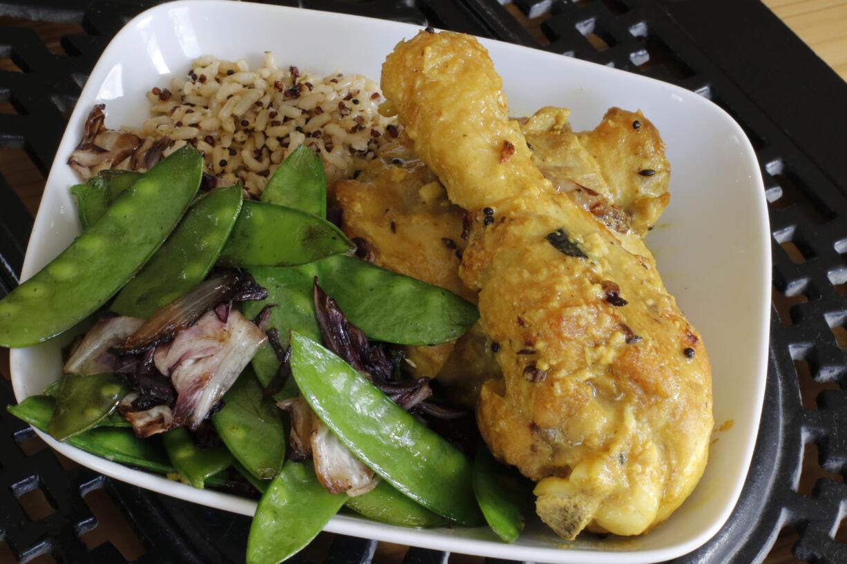 This March 21, 2016 photo shows buttermilk chicken kadhi with sides of multigrain rice and sauteed snow peas and radicchio in Concord, N.H. Kadhi is a classic and comforting Indian dish that braises chicken legs in a tart, gently spiced buttermilk sauce. (AP Photo/J.M.