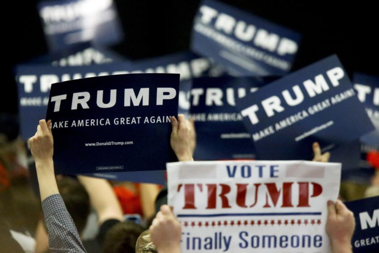 Supporters wave signs for Republican presidential candidate Donald Trump as he speaks during a campaign rally in Pittsburgh, Wednesday, April 13, 2016.