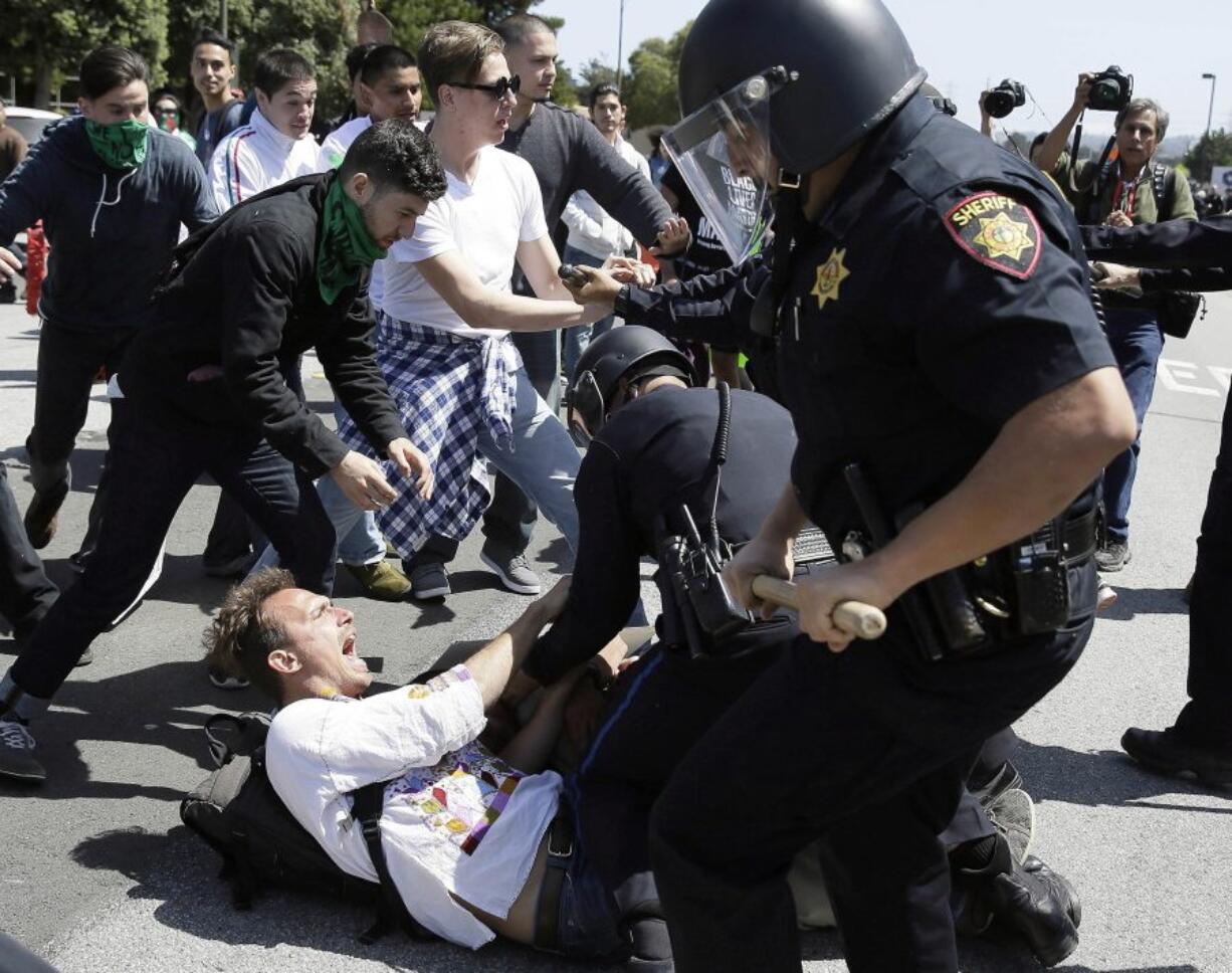 Police officers take a man into custody Friday at a protest against Republican presidential candidate Donald Trump outside of the Hyatt Regency hotel in Burlingame, Calif.