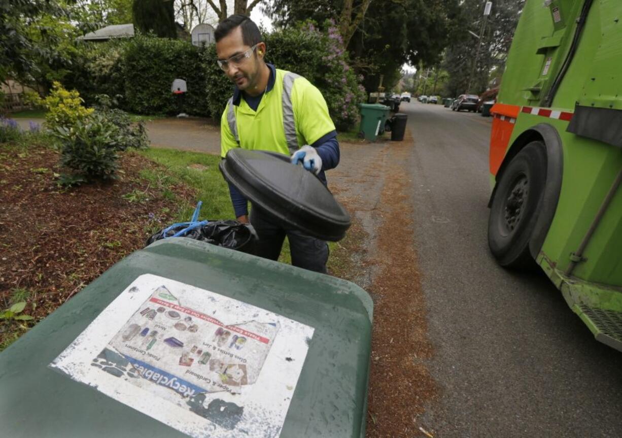 David Morales, a garbage driver with Recology, picks up a garbage container Friday for Seattle Public Utilities. A judge heard a challenge Friday to a new Seattle law allowing garbage collectors to check people&#039;s trash to see if they are disposing of recycling items and food waste incorrectly. (Ted S.