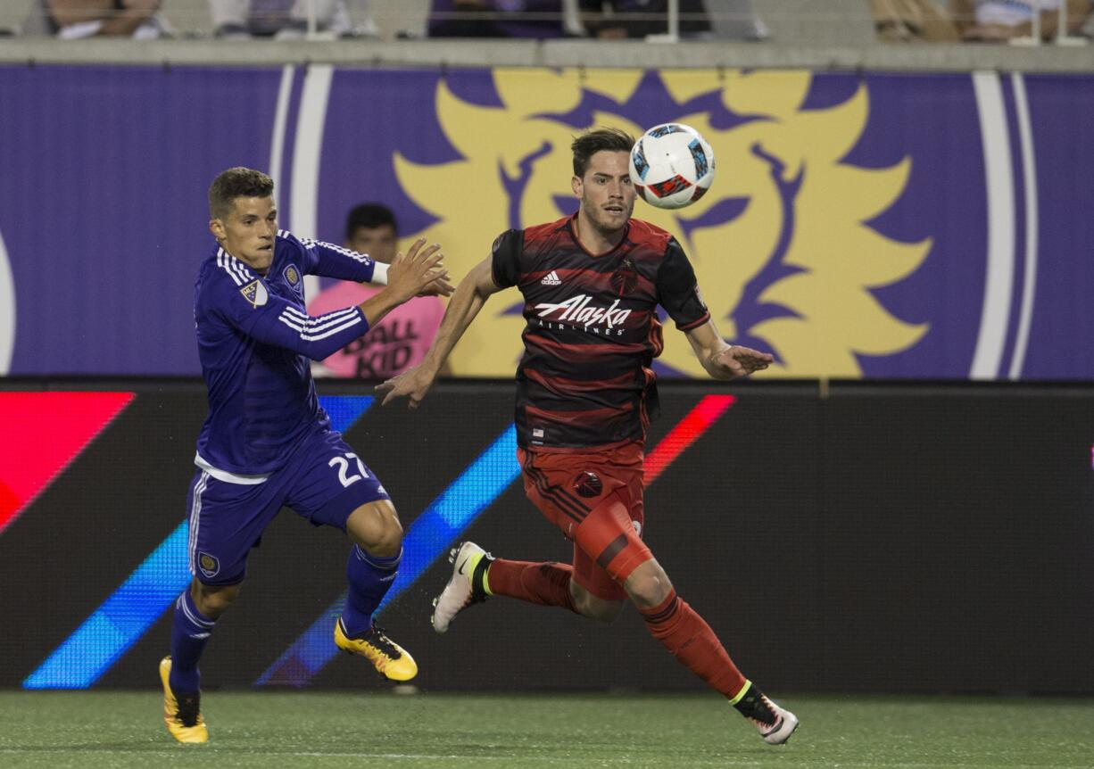 Portland Timbers forward Lucas Melano, right, follows the ball while being defended by Orlando City FC defender Rafael Ramos in the first half of an MLS soccer game, Sunday, April 3, 2016, in Orlando, Fla.