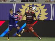 Portland Timbers forward Lucas Melano, right, follows the ball while being defended by Orlando City FC defender Rafael Ramos in the first half of an MLS soccer game, Sunday, April 3, 2016, in Orlando, Fla.