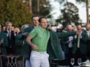 Defending champion Jordan Spieth, left, helps 2016 Masters champion Danny Willett, of England, put on his green jacket following the final round of the Masters golf tournament Sunday, April 10, 2016, in Augusta, Ga.